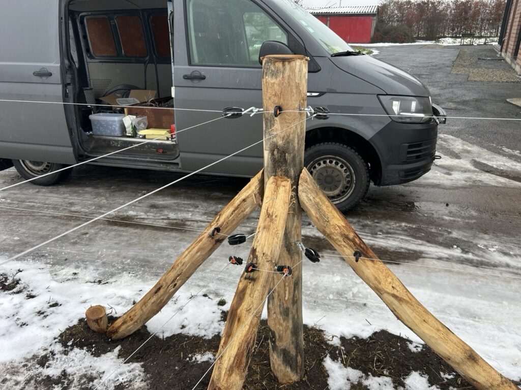 Robuuste houten omheining met isolatoren en metalen draad voor dieren op sneeuwgrond naast bestelwagen