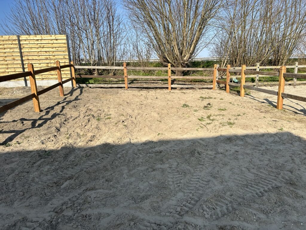 houten paardenomheining met planken en zandbodem in buitenruimte bij Nieuwlandzicht