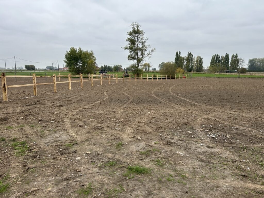 houten afrastering voor paardenweide op landelijke open akker met bomen op achtergrond
