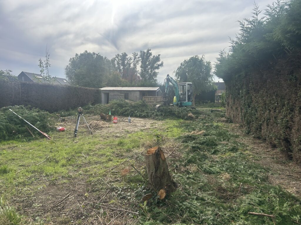 Terreinwerk met graafmachine en gemaaide heg, voorbereid voor installatie van dierenomheining